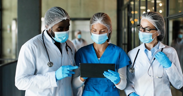 Male and female doctors using tablet and discussing lab reports.